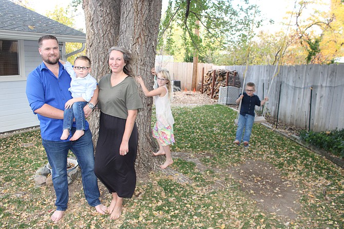 Jason and Brenda Klug holding 3-year-old Ira, with 7-year-old Daisy and 5-year-old Ronan in the background, at Jason’s parents’ house in Carson City on Oct. 24.