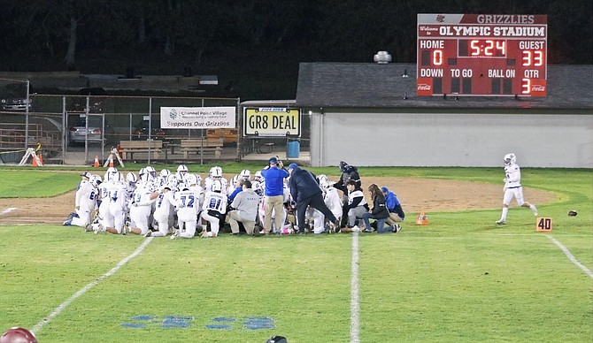 The Eatonville Cruiser football team kneels for a moment of silence for fallen teammate Jason Naro following the field goal that put the score at 33, Naro's jersey number.