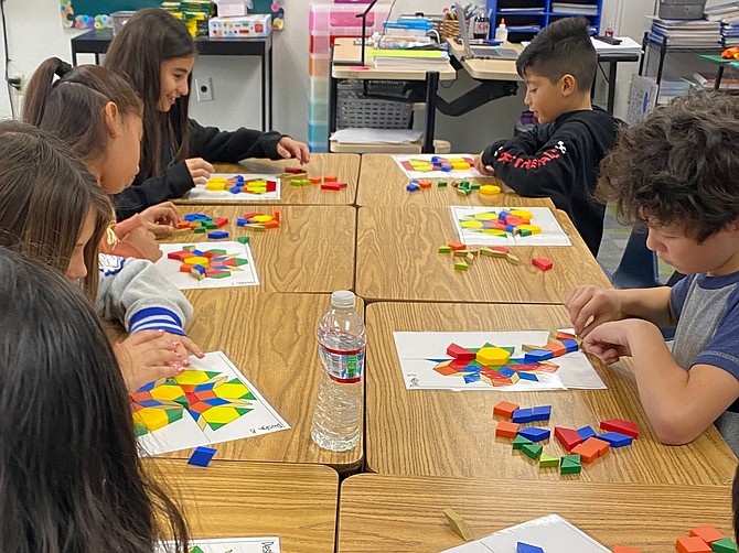 Students engage in symmetry and fraction tasks using pattern blocks.