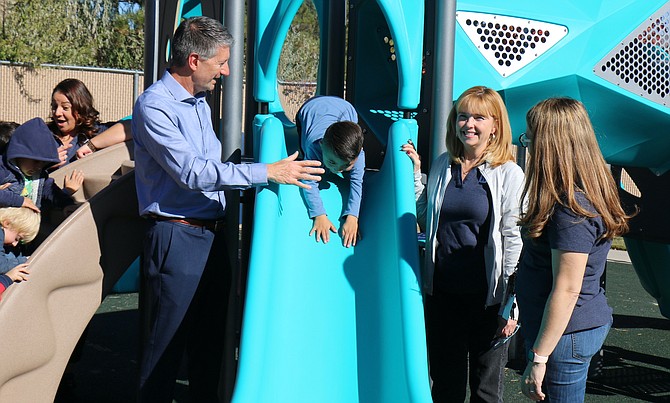 WNC President Kyle Dalpe attempts to high-five Childhood Development Center student Sebastian as he nosedives down a slide on the facility’s new playground set on Nov. 3, 2023 as Niki Gladys, executive director of Advancement, and CDC director Annalisa Acosta watch.