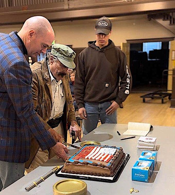 Organizer Steven Miller helps oldest Marine Bob Hammond cut the cake as youngest Marine Dan Fierle, far right, waits for a piece on Friday. Photo special to The R-C by Marine veteran and former Douglas County Emergency Dispatcher Destiny Perkins.