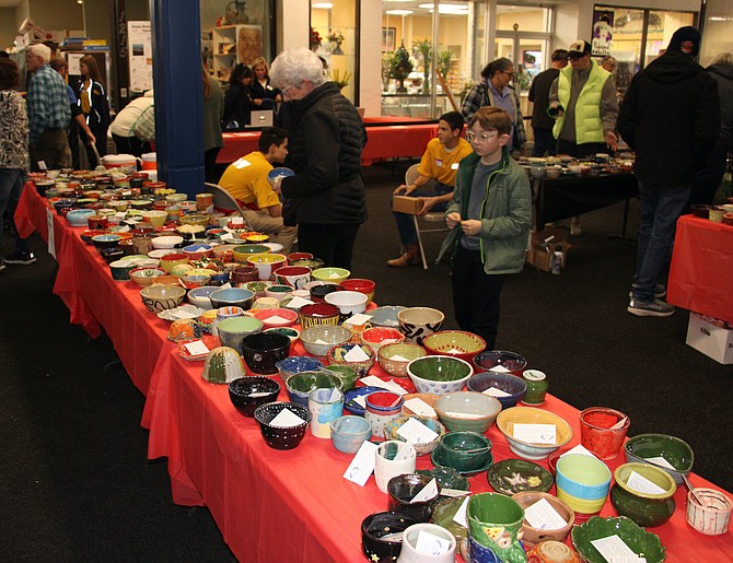 1 Peggy Epidendio, center, and 10-year-old Toshi Kuniya, right, looking at bowls at the Empty Bowls event at Carson Mall on Friday.