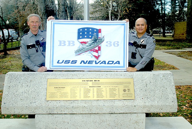 Nevada Capitol Police officers Steve Fleischmann, left, and Tom Pascua prepare to raise a new USS Nevada flag on Thursday behind the state Capitol. Both the United States and USS Nevada flags later flap in the breeze at half-staff.