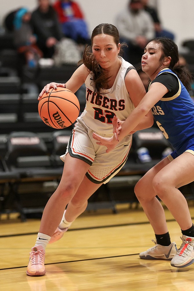 Douglas High senior guard Sky Rasmussen dribbles around a Reed defender Friday night, during the Tigers’ 56-21 win over the Raiders.
