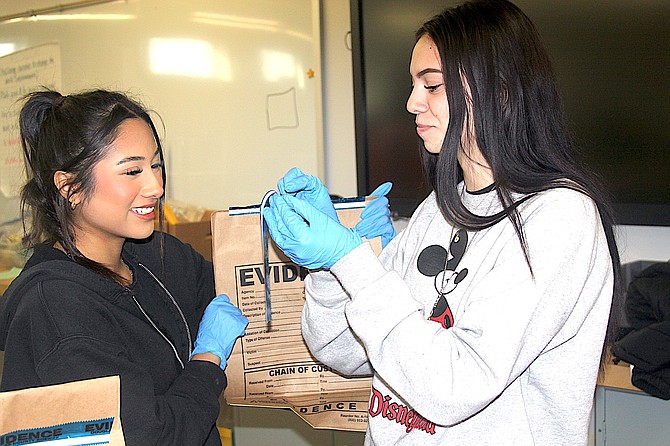 Douglas High School juniors Juli Tapia and Mazy Montoya tape up evidence from the crime scene during a mock homicide in Kimberly Tretton’s Forensics class Tuesday.