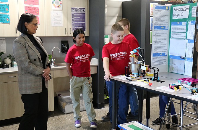 State Superintendent Jhone Ebert listens to Eagle Valley Middle School students Nicholas Budd, eighth grade, in front of the mixer, Kassandra Mosqueda, sixth grade, center, and Allen Riley explain how they applied Legos to practical uses such as creating an improved grip on mixers to help people with arthritis.