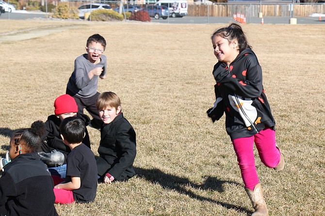 Arlo Gelsone, 7, back left in a gray shirt, starts a chase in “Duck, Duck, Goose” at Fritsch Elementary School. The game was adapted to his needs with students rubbing each other’s heads to indicate who they choose to chase.