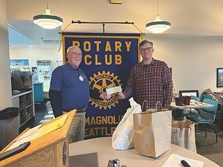 Bruce McWalter, president of the Rotary Club of Magnolia, presents a check to Matthew Carr of the Ballard Food Bank.