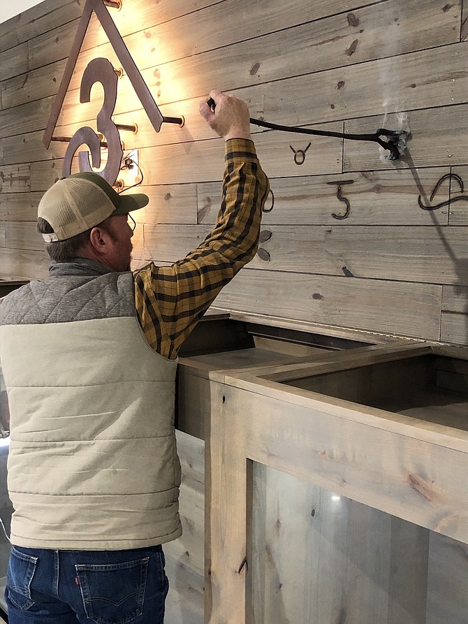 Tyson Torvik brands the wall of the state’s branding iron exhibit earlier this month.