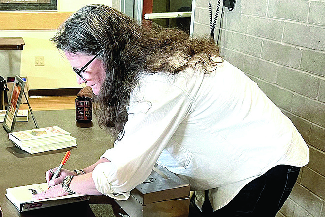 Author Clare Frank signs a copy of her book ‘Burnt — A Memoir of Firefighting’ At the Friends of the Library annual meeting on Jan. 27.