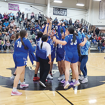 The McDermitt High School girls basketball team celebrates after receiving the championship trophy,