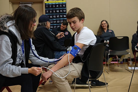 Christine Albright, a nurse volunteer with the Nick of Time Foundation, checks the blood pressure of Owen Rainey, 14, an eighth grader at Valley View Middle School.