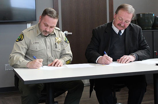 Sheriff Adam Fortney and County Executive Dave Somers sign the agreement at an announcement event held in the Carnegie Resource Center in Everett Tuesday, Feb. 21.