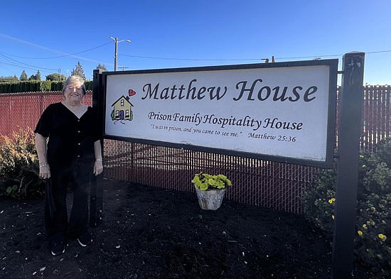 Linda Paz, the director of Matthew House, poses next to Matthew House's sign Oct. 11.