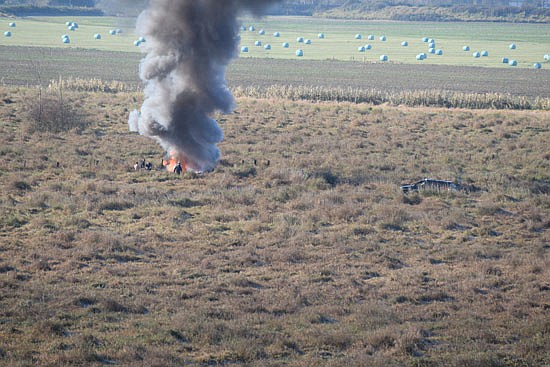 A column of dark smoke rose from the fire at the crash site, as seen the morning of the crash with authorities attending.