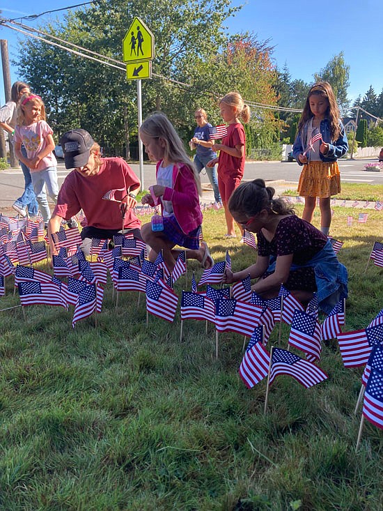A small set of students in Lorraine Burnell’s combined class of kindergarten to 2nd grade each plant American flags on The Academy of Snohomish’s lawn during their recess Sept. 8.