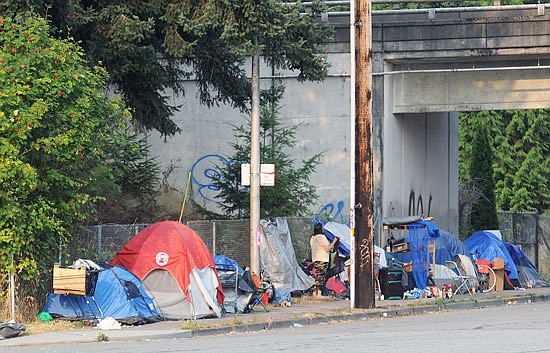 Tents and belongings of homeless campers block the sidewalk and a bus stop on Everett Avenue at the Interstate 5 underpass Aug. 14.