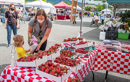 In July 2020, Reagan, age 2½, and mom Ashley from Monroe buy raspberries from the Lopez Bros. Farms stall at the Monroe Farmers Market, on Wednesday, June 24, in the parking lot of Galaxy Theatre. The market featured fruit, veggies, face shields and barbecued food. Other vendors offered metal and craft items for sale.