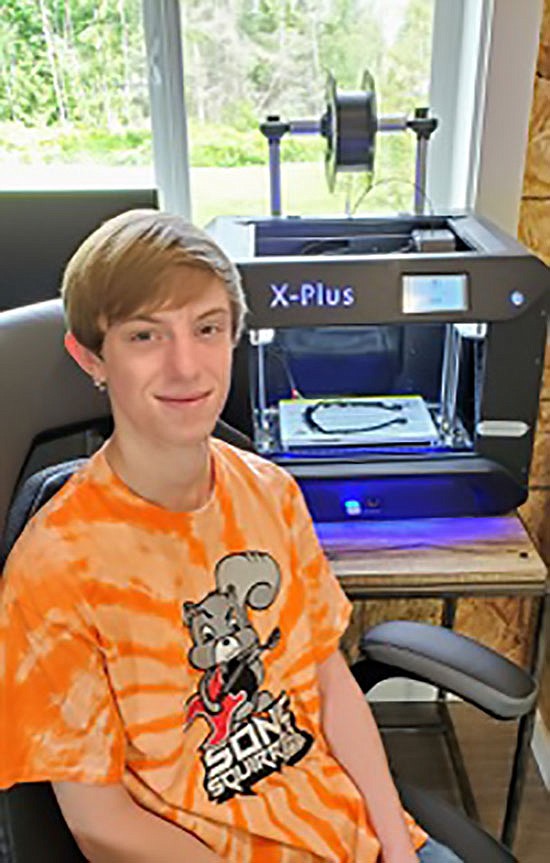 Glacier Peak High senior Dylan Reiner, part of the Sonic Squirrels team, sits with a 3D printer used to make personal protective equipment parts.