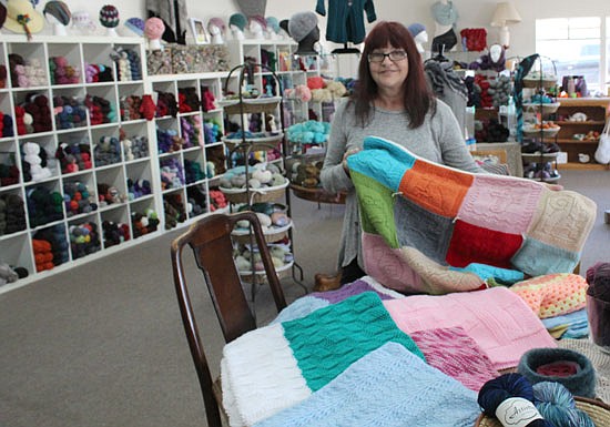 Teresa Wilson, owner and operator of Country Yarns for the last 15 years, holds one of many blankets made by volunteers. Blankets ready to be delivered to Domestic Violence Services of Snohomish County are dropped off at Country Yarns and delivered by Hope or Wilson.
