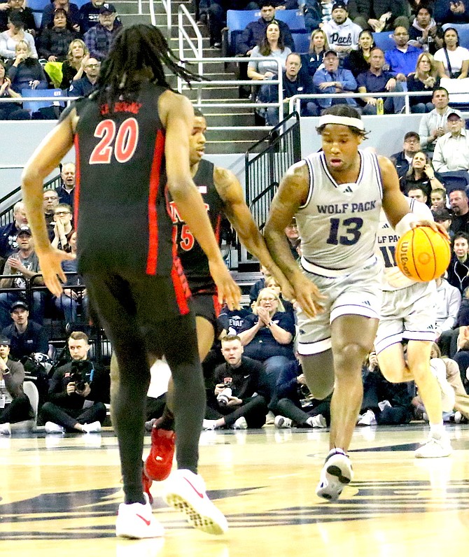 Playing in his final game at Lawlor Events Center, Nevada senior Kenan Blackshear (13) dribbles past UNLV's Luis Rodriguez (15) and (20) Keylan Boone in the first half of Nevada's 75-65 win against their in-state rivals. The Wolf Pack men's basketball team played their final home game to a packed house.