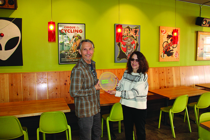 Donna Walden, right, hands Tim Healion of Laughing Planet a circular display for joining the Reno/Sparks Green Dining District.