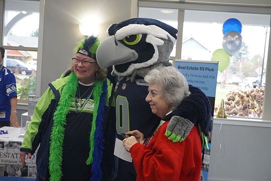 Carol Amisson, of Snohomish, and Pam Gross of Snohomish smile for a friend to take a photo of them with Seattle Seahawks mascot Blitz, who stopped by the Snohomish Senior Center Thursday, Dec. 14 together with two retired Seahawks players.
