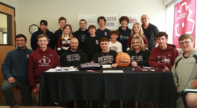 Sierra Lutheran’s Marcus Jones, front row middle, smiles alongside his teammates, friends, coaches and family after signing his National Letter of Intent to play basketball at Bethel College in North Newton, Kansas.