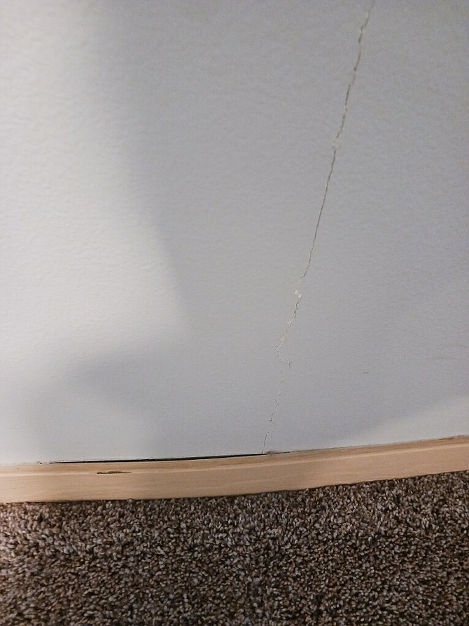 Resident Nicole Leith found water-bowed base molding and new damage such as this crack in her walls in her old apartment which apartment management said was safe to move back into before reneging and saying it wasn’t ready because it didn’t pass city inspection.