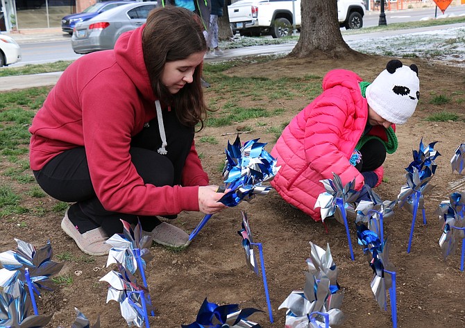 Eleanor Woodrum, 15, who attends Carson High School, and Phoebe Ward, 9, who is homeschooled, plant pinwheels Friday in front of the Nevada Legislature for National Child Abuse Prevention Month.