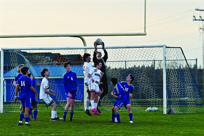 Eatonville goalkeeper Nate Goode soars above the pack to secure a shot on goal from Montesano.