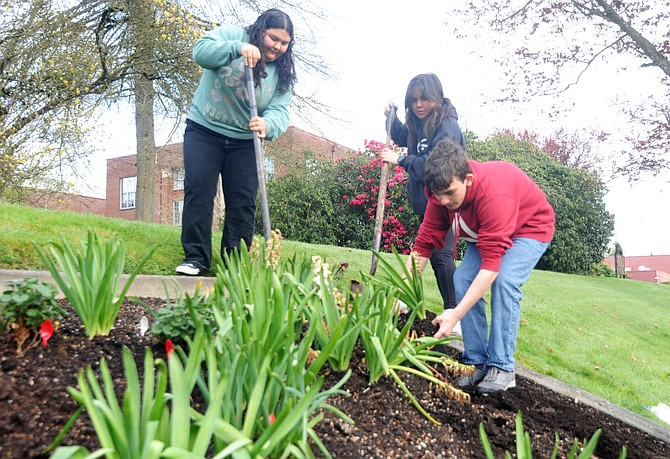 Snohomish High School horticulture class students, from left to right sophomore Corina Ramirez, junior Madison Porter, and sophomore Karsyn Whitaker work to place fresh blooming flowers into the 2024 planting display in front of the high school on Wednesday, April 17. The students removed earlier placed hyacinths which had finished blooming 
with geraniums.