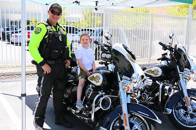 Deputy Michael Jerauld of the Carson City Sheriff’s Office traffic division smiles with Liam Silva, 5, after placing him on a motorcycle during Saturday’s Cops and Kids event.