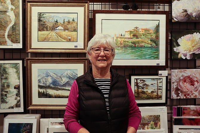 Joan Pinney standing in front of her water color paintings inside the Arts of Snohomish Gallery. Pinney is one of the founding members of the gallery, and has been working in watercolor since the 1980s.