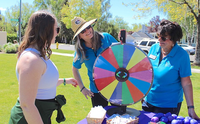 Daria Winslow, Amy Roby and Debbie Posnien spin the wheel at the Mental Health Awareness Walk and Resource Fair on Saturday.