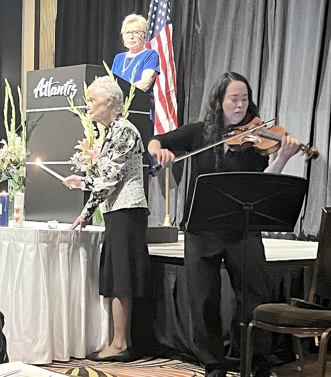 At the podium is Judith Shumer, co-chair of Holocaust Day of Remembrance. After the presentation, a candle lighting ceremony remembers the 6 million Jews who were killed during World War II. Playing the violin is Claire Tomoko Tatman from the Reno Philharmonic.