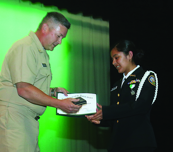 Instructor Lt. Cmdr. Jason Bardin, left, presents an award to Junior ROTC cadet Sandra Marquez Garcia.