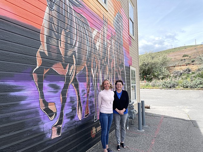 Melanie Thomas (left), incoming chair of the Carson City Chamber of Commerce’s Board of Directors, and Stacy Woodbury, outgoing chair, in front of a mural on the side of the chamber’s offices in Carson City on June 3, 2024.