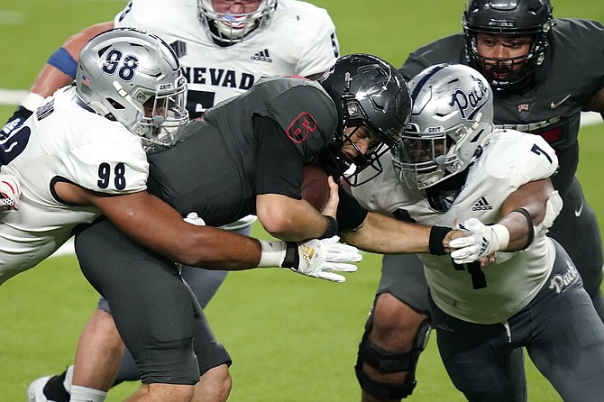 Nevada defensive end Sam Hammond, left, and defensive end Kameron Toomer sack UNLV quarterback Max Gilliam during the Fremont Cannon game on Oct. 31, 2020, in Las Vegas.