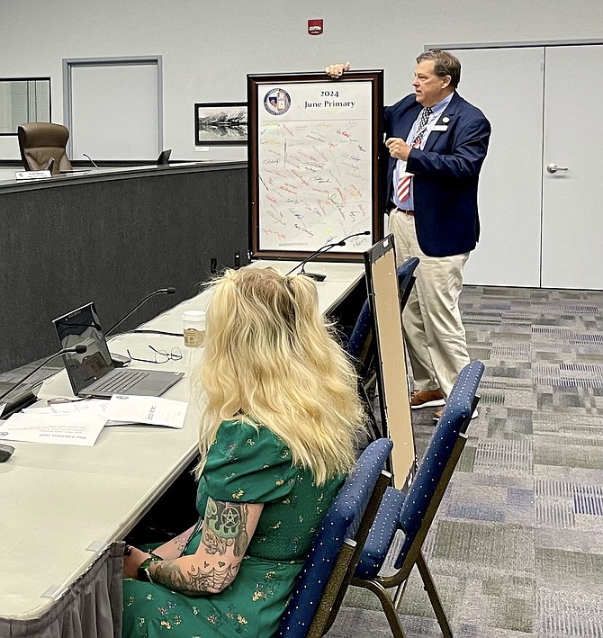 Carson City Deputy Clerk of Elections Emily Toups, front, and Clerk-Recorder Scott Hoen holding up signatures of poll workers to publicly thank them during the official canvass of the vote by the Board of Supervisors on June 21, 2024.