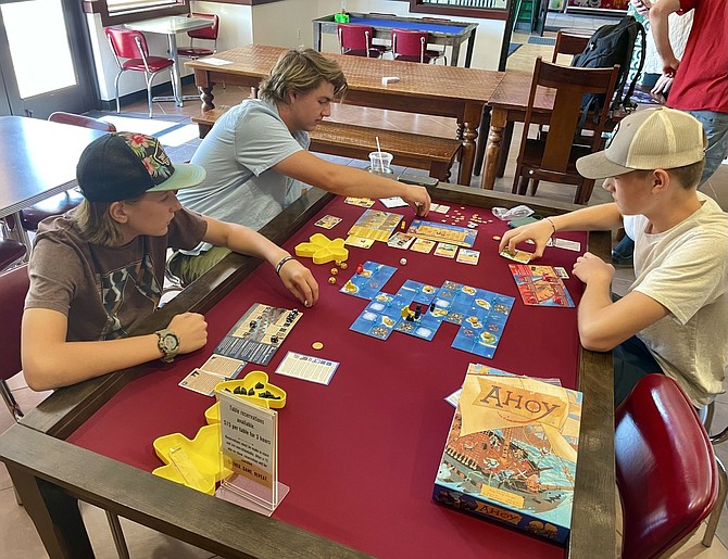 From lower left and clockwise, Gideon Scholz, 13, Isaac Vaughn, 17, and J.J. Scholz, 16, at 3 Arrows Games in Carson City on July 11, playing ‘Ahoy,’ which they described as a strategic pirate game.