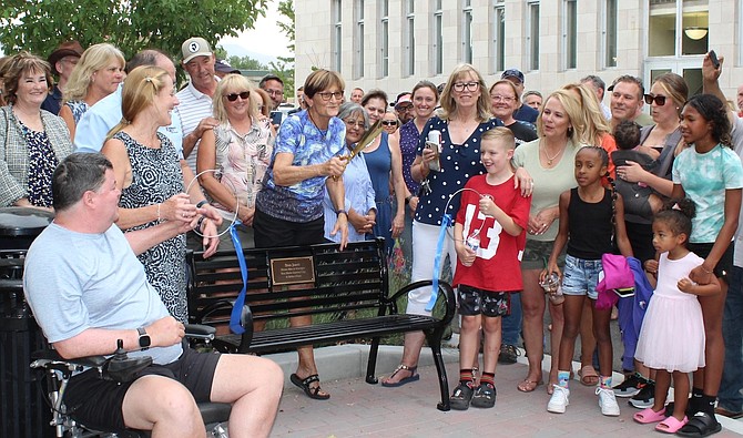 Sue Jones holding the scissors during a bench donation in Carson City July 12 in honor of late husband Stan Jones. Donors Jed and Susie Block are pictured to her left, and to the right are Stan Jones’ family members.