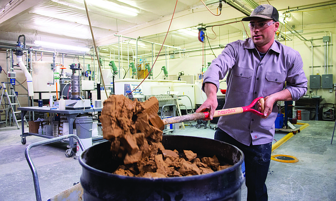 A Lithium Americas pilot plant technician shovels tailings into a bin after they went through a lithium extraction process at the company’s test plant in Reno.