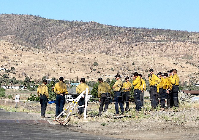 A crew of firefighters meets along Highway 395 and Spring Valley Road on Thursday morning after a long night battling the fire.