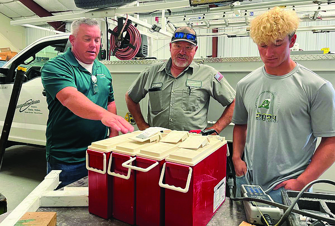 CC Communications intern James Kelsey, right, learns from Matt Hyde, left, and Larry Burchard how to test the batteries used in the company’s battery back-up stations.