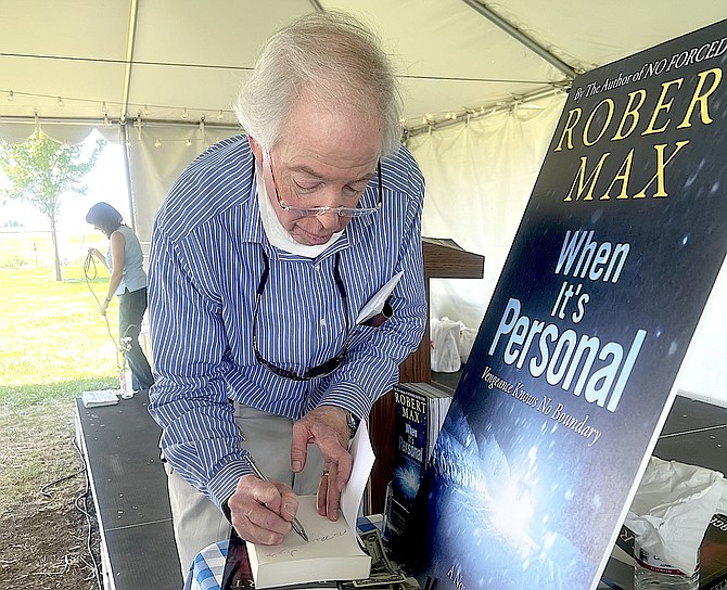 Barb Geibel took a picture of novelist Robert Max signing one of his books at the Dangberg Home Ranch Historic Park on Saturday. This weekend and next speakers shift from crime to Twain.