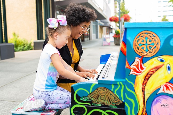 Sophia Mendez (right) and Nadya Mendez (left) of Everett sit down on Colby Avenue in downtown Everett to play a piece during a prior year’s annual Street Tunes event.