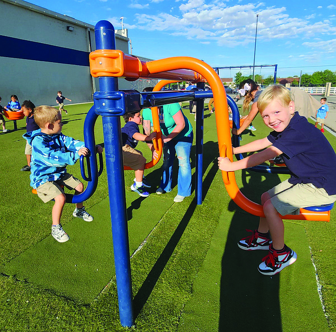 Peirce Ferguson, right, enjoys some swinging time on Oasis Academy’s playground equipment.