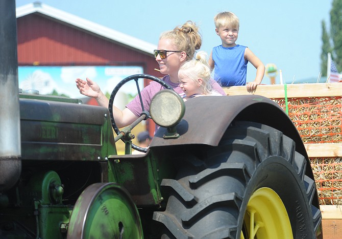 Skye Johnson of Monroe drives her family’s 1941 John Deere farm tractor while holding her two-year-old daughter Blakeley in her lap as her son Brody, 4, rides in the hay wagon, as they participate in the grand parade of tractors at the Sky Valley Stock and Antique Tractor club’s annual Tractor Show and Threshing Bee Saturday, Aug. 10. For its 35th annual show, the club’s event was held at Bob’s Corn farm south of Snohomish this year. The event featured the display of tractors and farming implements of all types and ages dating as far back as the 1920s. Other event activities featured tractor pull competitions, driving skills competitions as well as demonstrations of the use of early threshing and baling machinery.