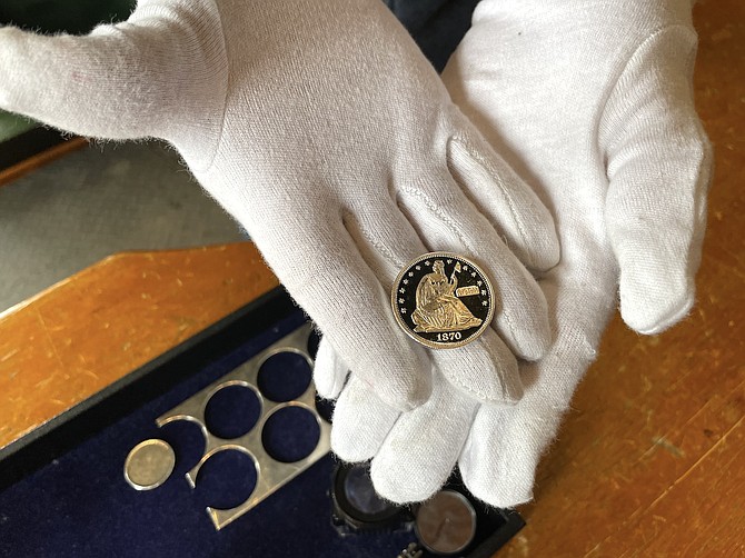 Woody Davis holds a reproduction of an 1870 half dollar from historic Coin Press No. 1 at the Nevada State Museum in 2023.